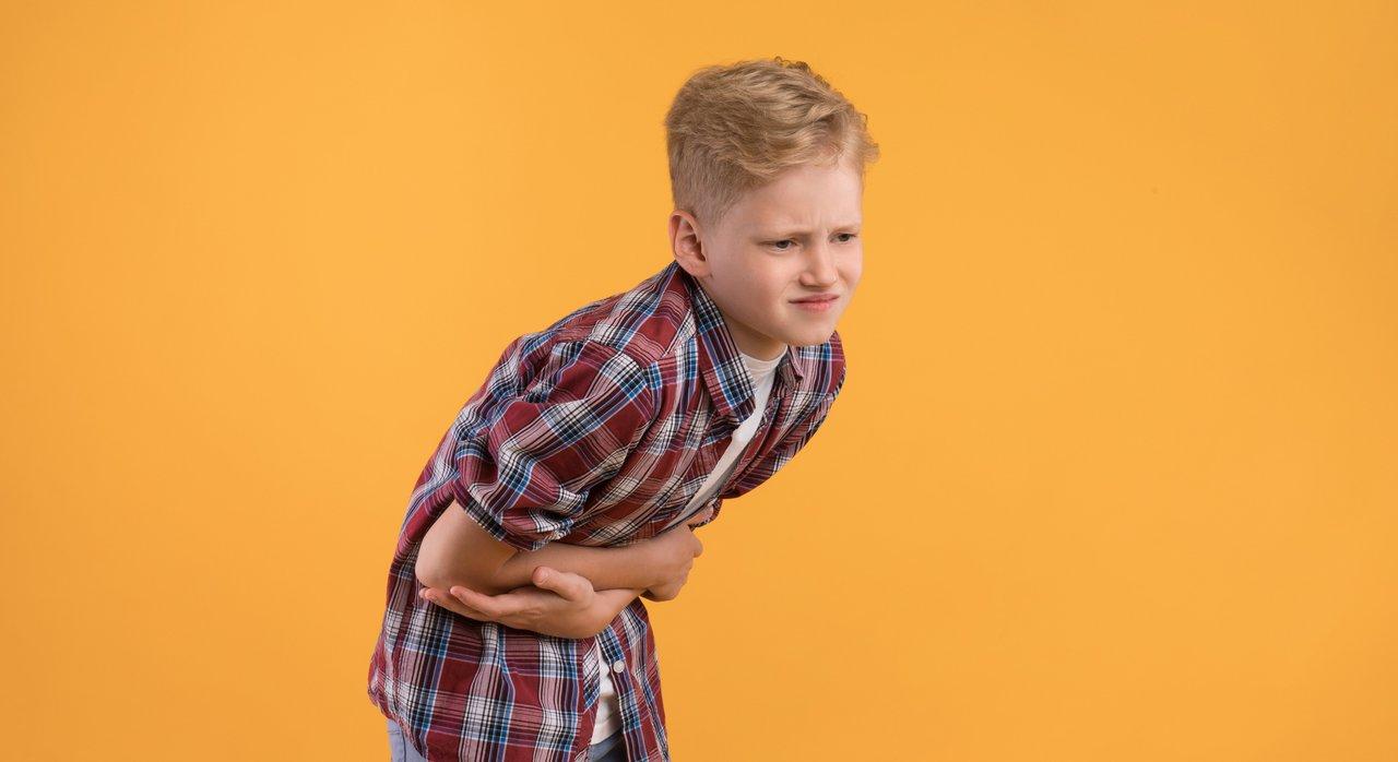 Enfant fatigué souffrant de maux d'estomac, symbole des troubles digestifs fréquents chez l’enfant.